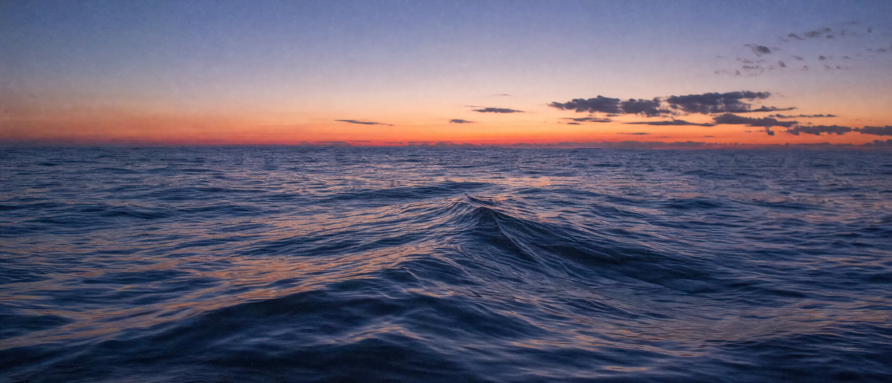 The open Atlantic at dusk under a rose and blue sky.